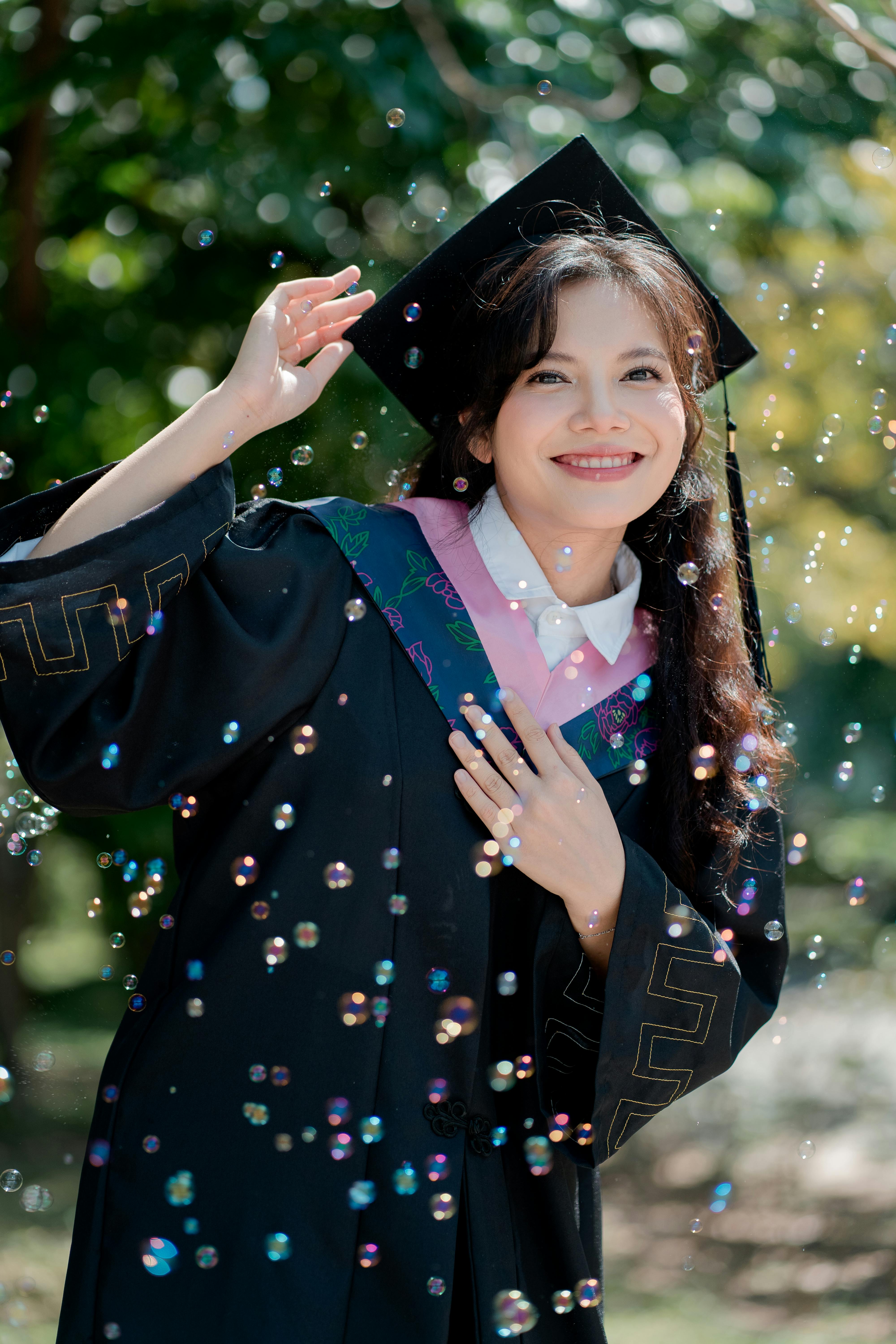 Happy graduate celebrating with bubbles in a sunny outdoor setting.